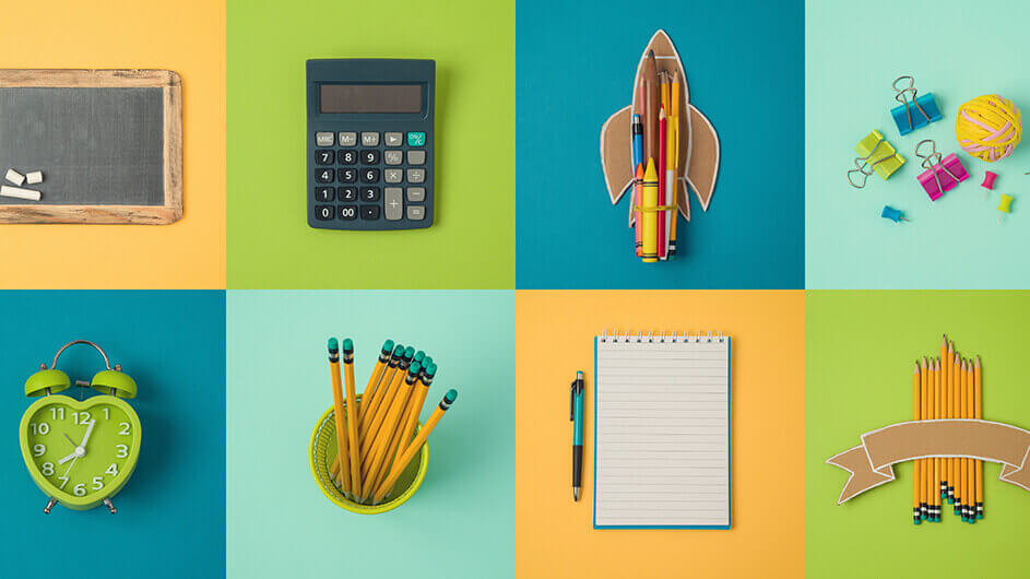 Aus der Vogelperspektive: Eine Collage mit Schulsachen: Eine Tafel mit Kreise, ein Taschenrechner, eine Rakete aus Pappe und Stiften, Reiszwecken und Klammern, ein Wecker, Bleistifte, ein Block mit Stift.