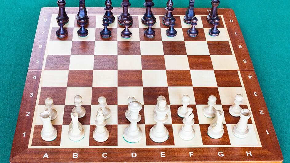 Aus der Vogelperspektive: Ein Schachbrett aus Holz mit Schachfiguren. Das Schachbrett hat eine Schachnotation.