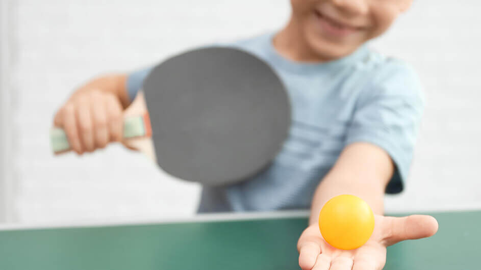 Lächender Junge mit Tischtennisball und Tischtennisschläger