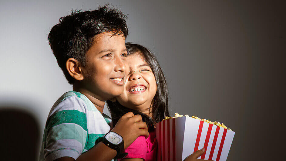 Fröhliche Geschwister im Kino mit Popcorn
