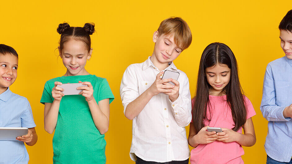 Lächelnde Kinder spielen oder lernen mit Kinder-Apps auf Smartphones und Tablets