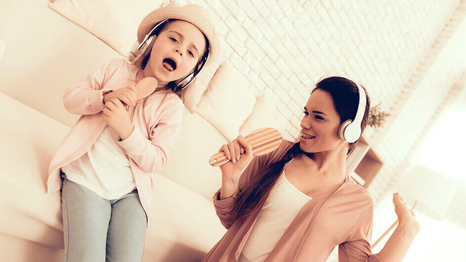 Mutter und Tochter singen mit Leidenschaft: beide haben Kopfhörer auf und singen in Haarbürsten, statt in Mikrofone.