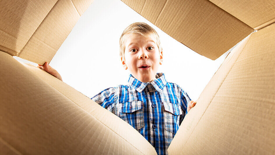 Aus der Froschperspektive: Ein Junge guckt von oben überrascht in ein Paket hinein