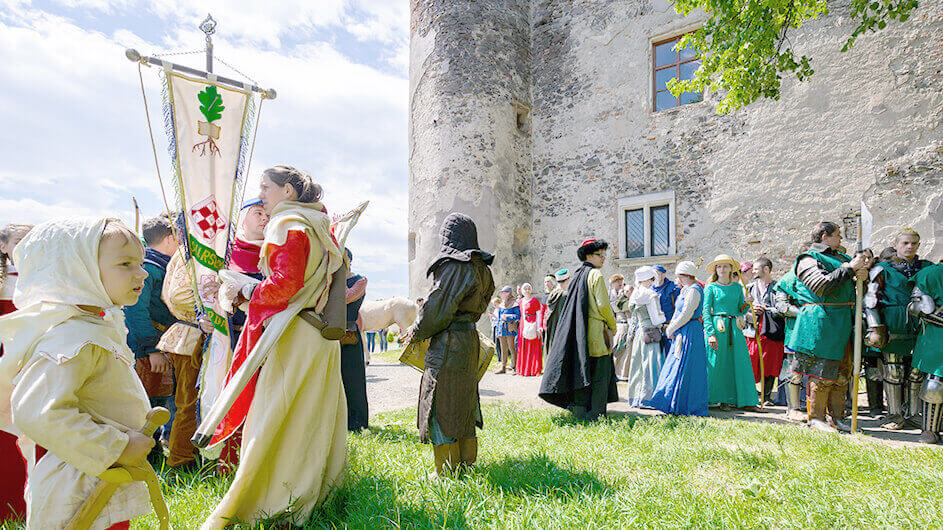 Ein Mittelalterfest bzw. Ritterfest vor einer Burg mit Kindern und vielen Gewandeten