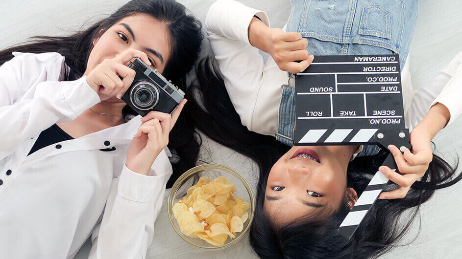 Zwei lächelnde Teenagerinnen mit Kamera und Filmklappe
