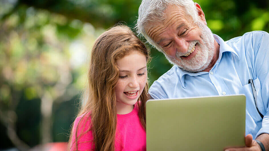 Eine Enkelin beobachtet mit ihrem Großvater über den Laptop Vögel