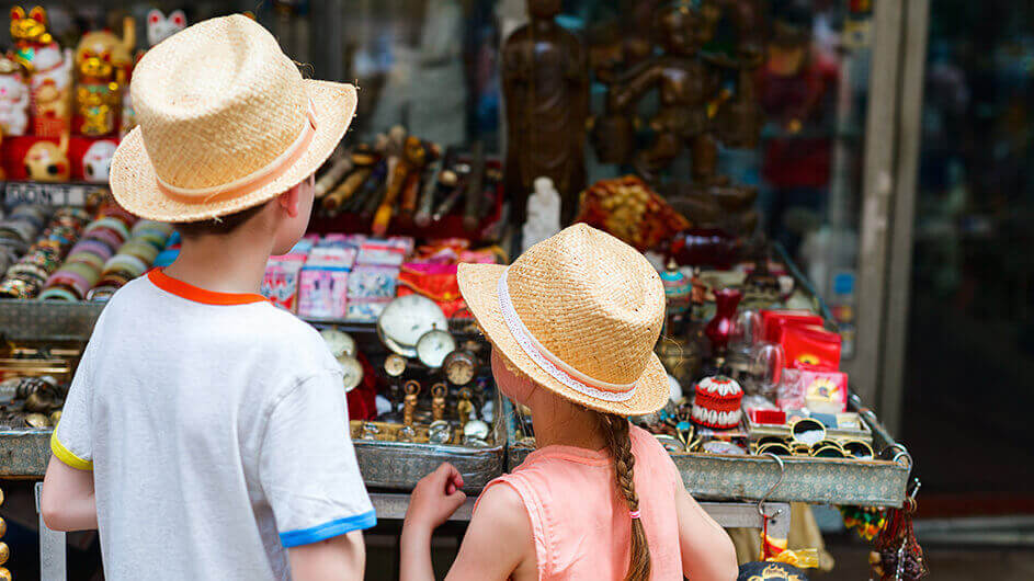 Zwei Kinder mit Strohhüten auf einem Kinderflohmarkt