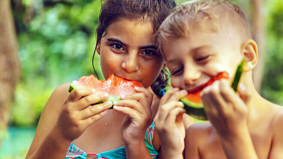 Zwei Kinder essen Wassermelone in einem Freibad