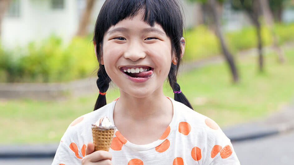 Ein lächelndes Mädchen beim Essen von Eiscreme in der Waffel