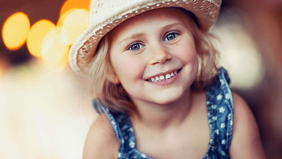 Ein kleines, lächelndes Mädchen mit einem Strohhut