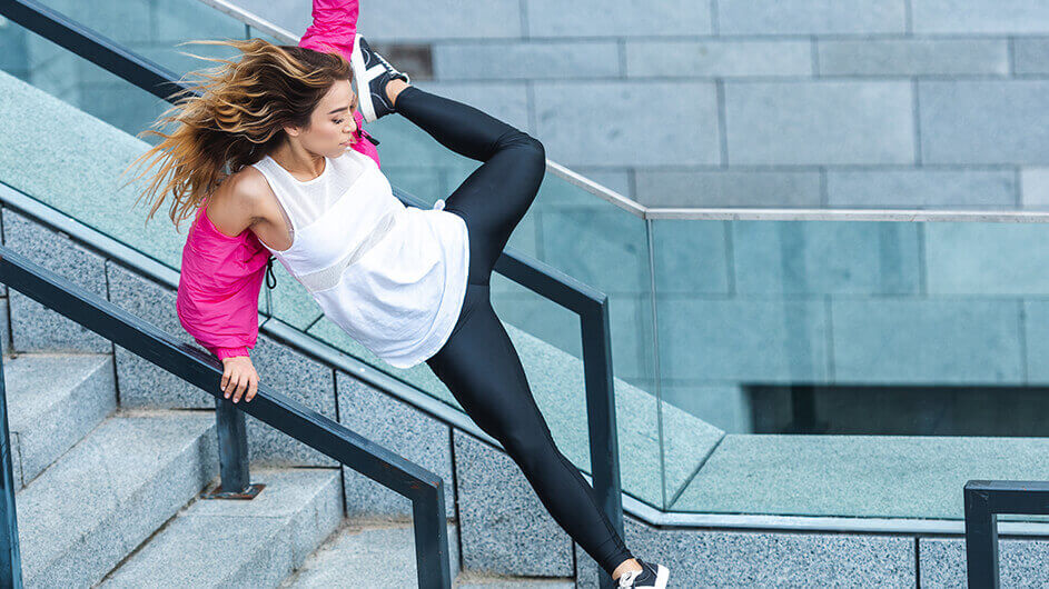 Eine junge Frau bzw. Teenagerin beim Parkour-Laufen: Sie springt cool eine Treppe hinab